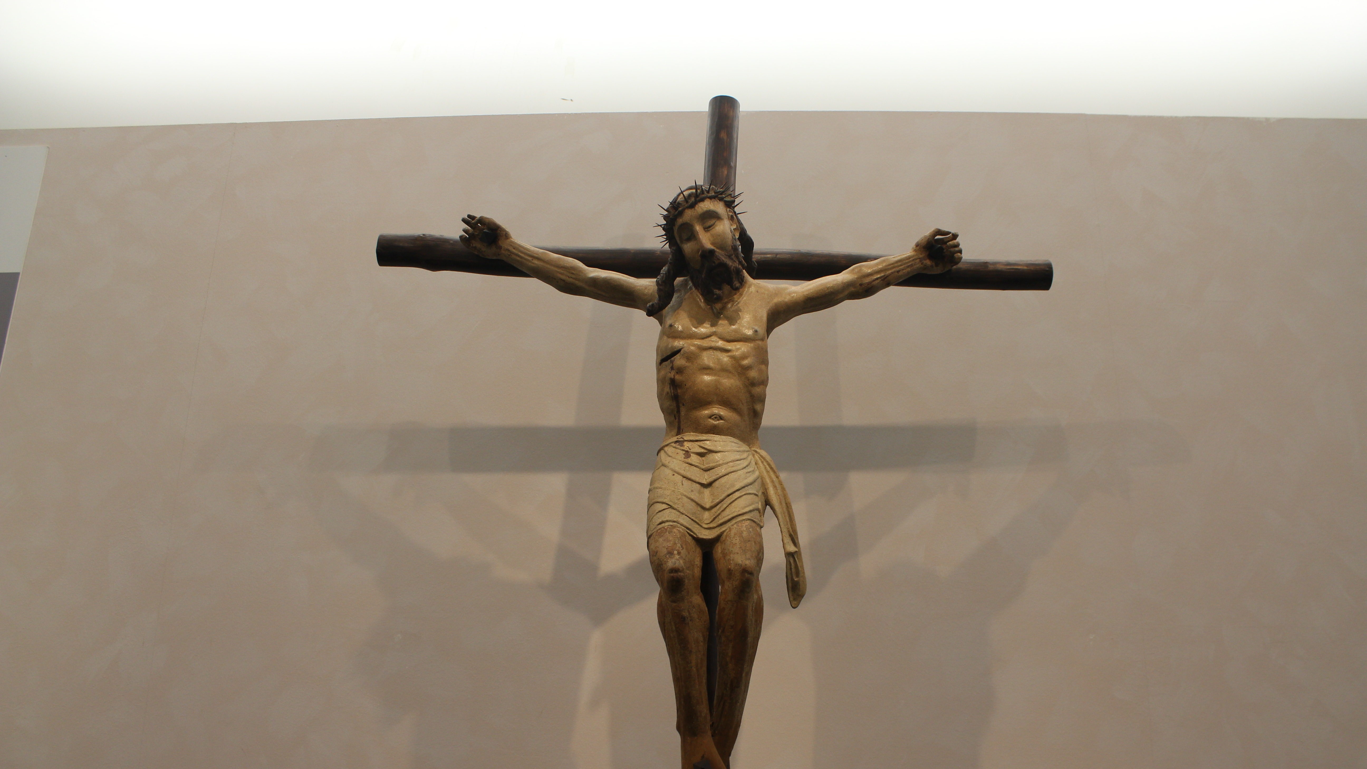 Statua in legno di Cristo crocifisso, con dettagli espressivi e una posa sofferente.