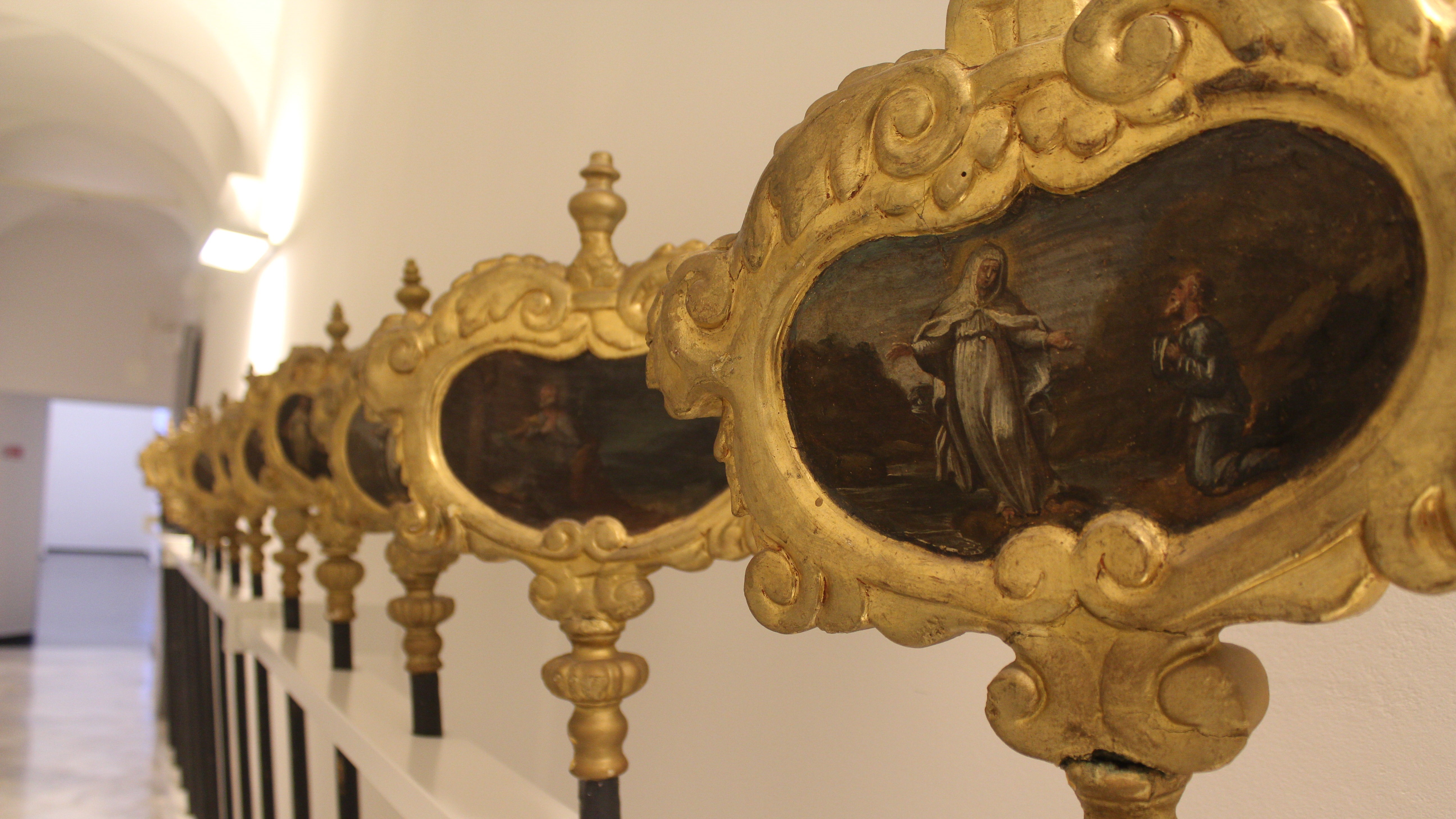 Dettaglio di antiche pale d’altare con raffigurazioni sacre incorniciate in oro.