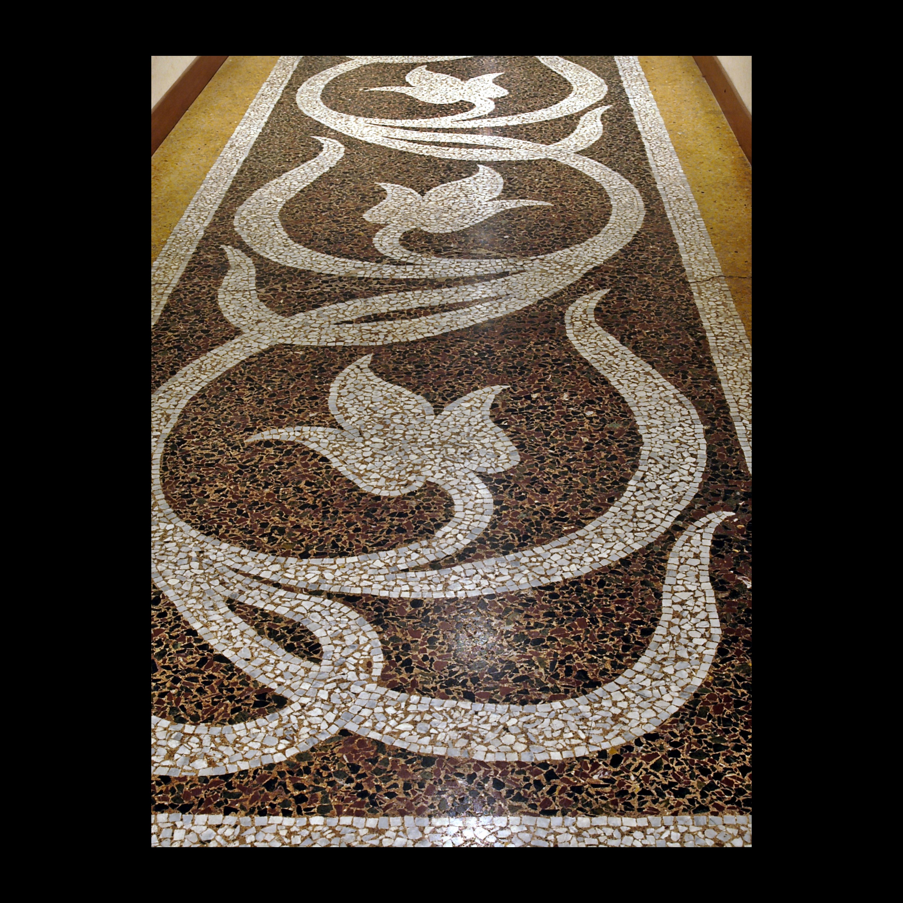 Dettaglio di un mosaico decorativo con motivi floreali bianchi su sfondo scuro.