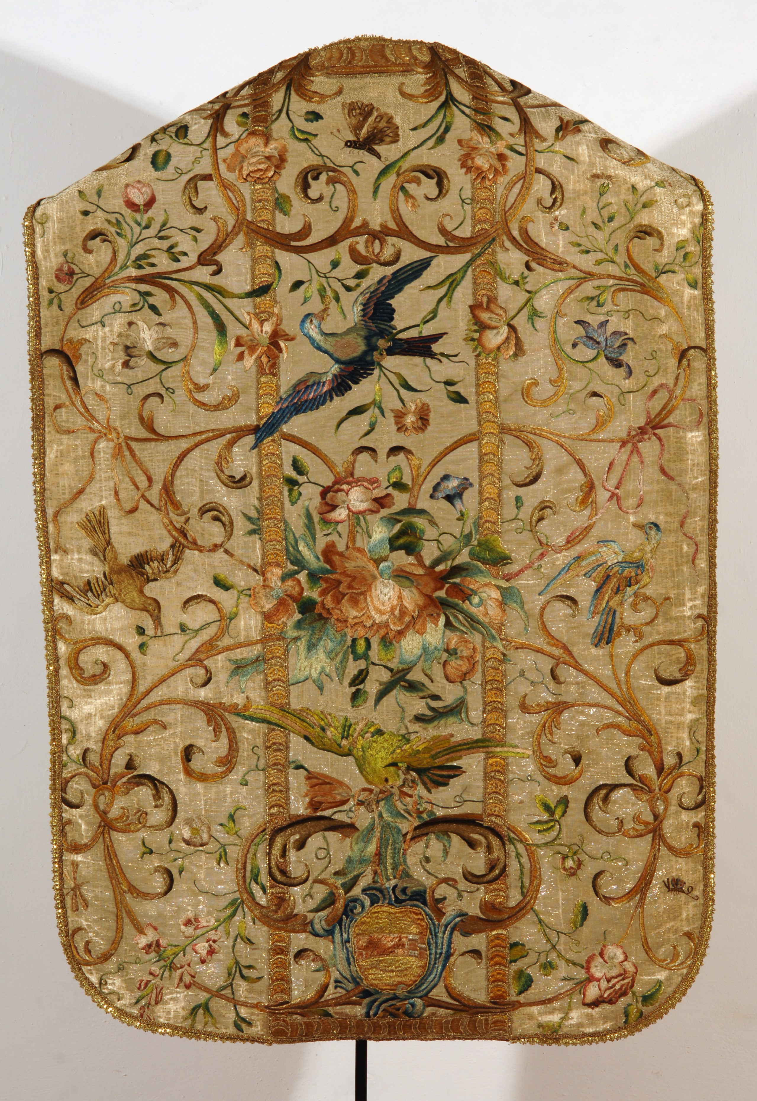 Paramento sacro decorato con motivi naturali e dettagli dorati.
